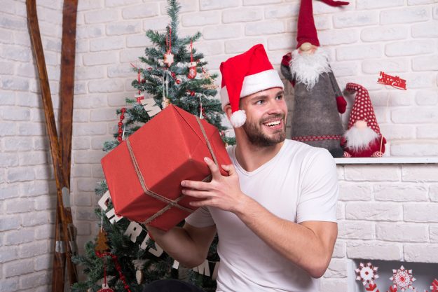 Man In Santa Hat Hold Christmas Present. Online Christmas Shoppi